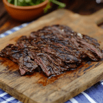 Sliced grilled beef on a wooden cutting board, perfectly cooked and juicy.